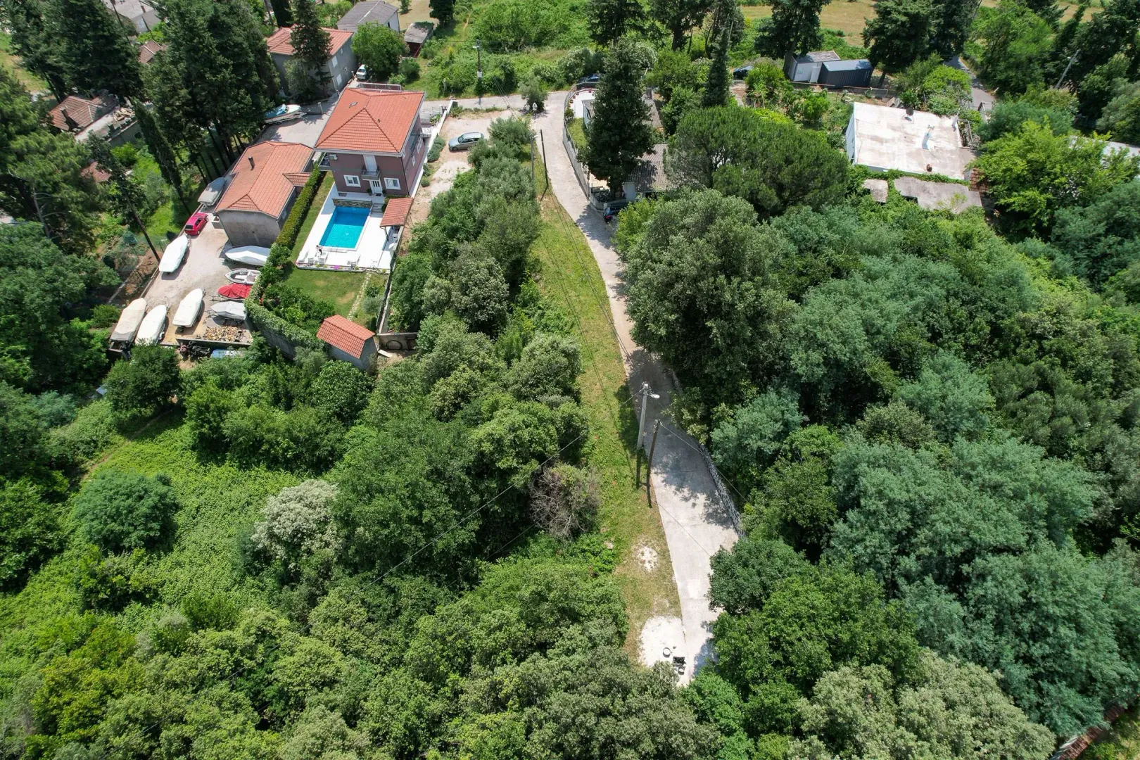 Pogled iz vazduha na kuću sa bazenom i okruženje puno zelenila.
