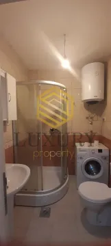Smaller bathroom with a shower cabin, sink, toilet, and washing machine. - image 11