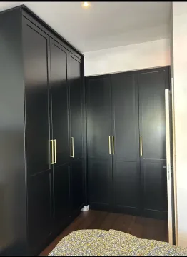 Spavaća soba sa ugradnim crnim ormarima sa zlatnim ručkama. - image 4