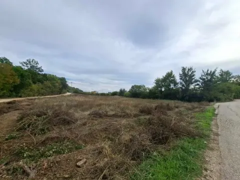 Pogled na prostrano građevinsko zemljište okruženo zelenilom i putem. - image 2