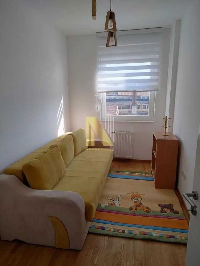 Manja dnevna soba sa žutim kaučem i tepihom.