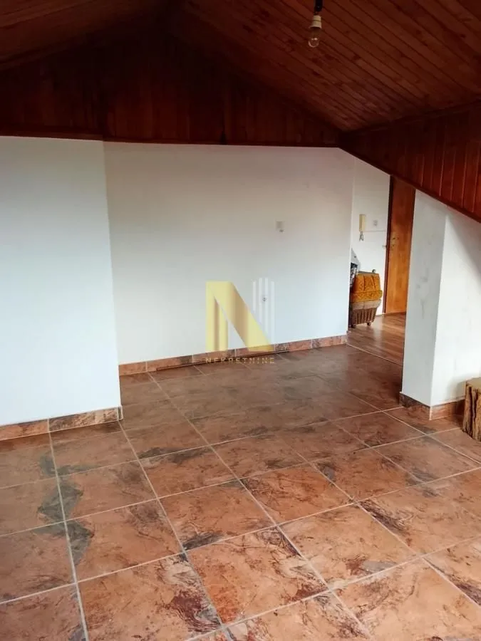 Prazna prostorija u potkrovlju sa popločanim podom i drvenim plafonom.