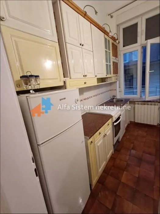 Small kitchen with white cabinets, a refrigerator, and an exterior window.