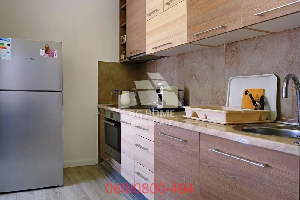 View of the kitchen with wooden cabinets and a refrigerator.