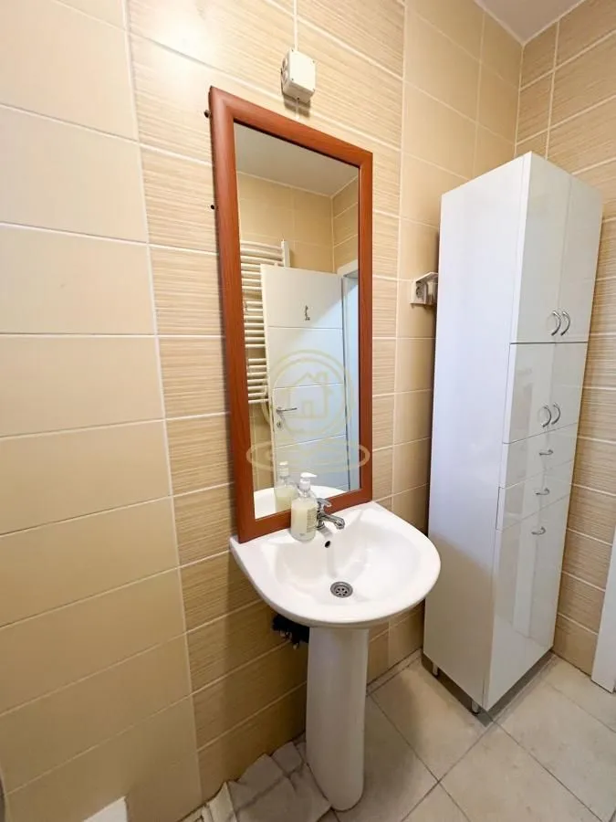 Kupatilo sa umivaonikom, ogledalom i belim ormarićem.