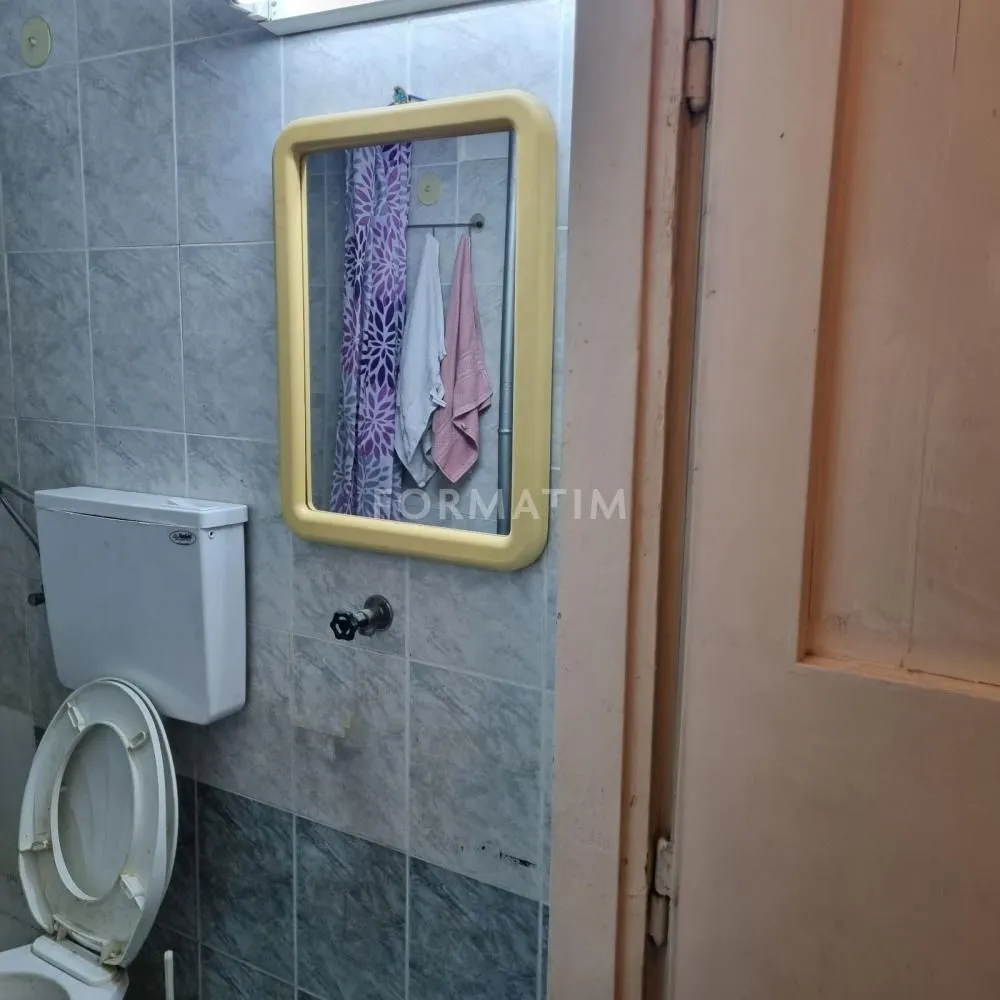 Small bathroom with tiled walls, toilet bowl, and mirror.