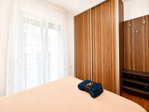 Spavaća soba sa bračnim krevetom, velikim drvenim garderoberom i balkonskim vratima. - image 5