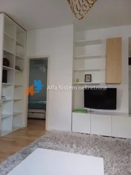 Dnevna soba sa belim regalom, televizorom i pogledom na spavaću sobu. - image 7