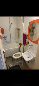 Small bathroom with a bathtub, toilet, and sink. - image 15
