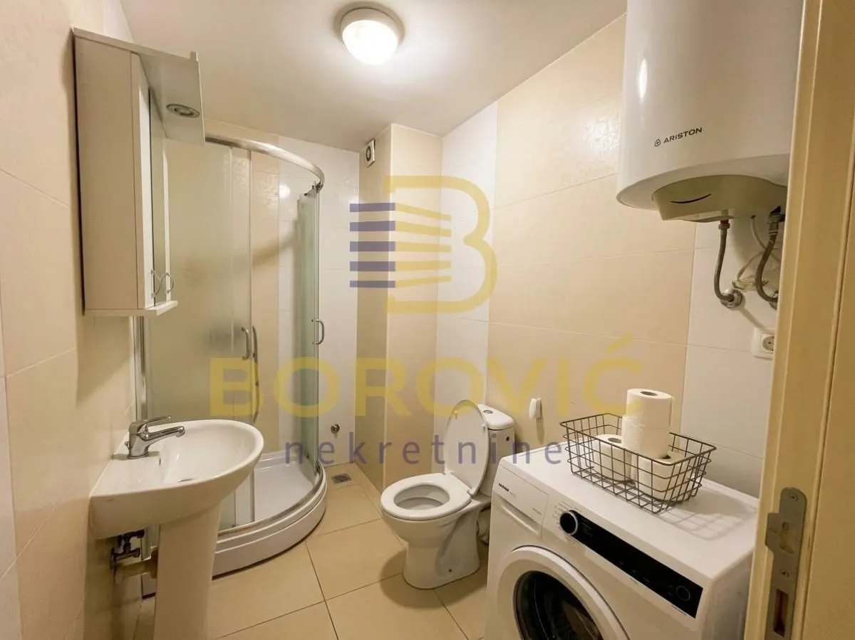 Bathroom equipped with a shower cabin, washbasin, toilet, and washing machine.