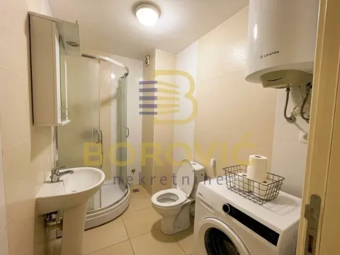 Bathroom equipped with a shower cabin, washbasin, toilet, and washing machine. - image 7