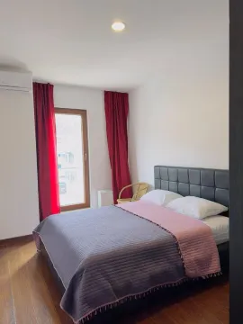 Spavaća soba sa bračnim krevetom, crvenim zavesama i klima uređajem. - image 9