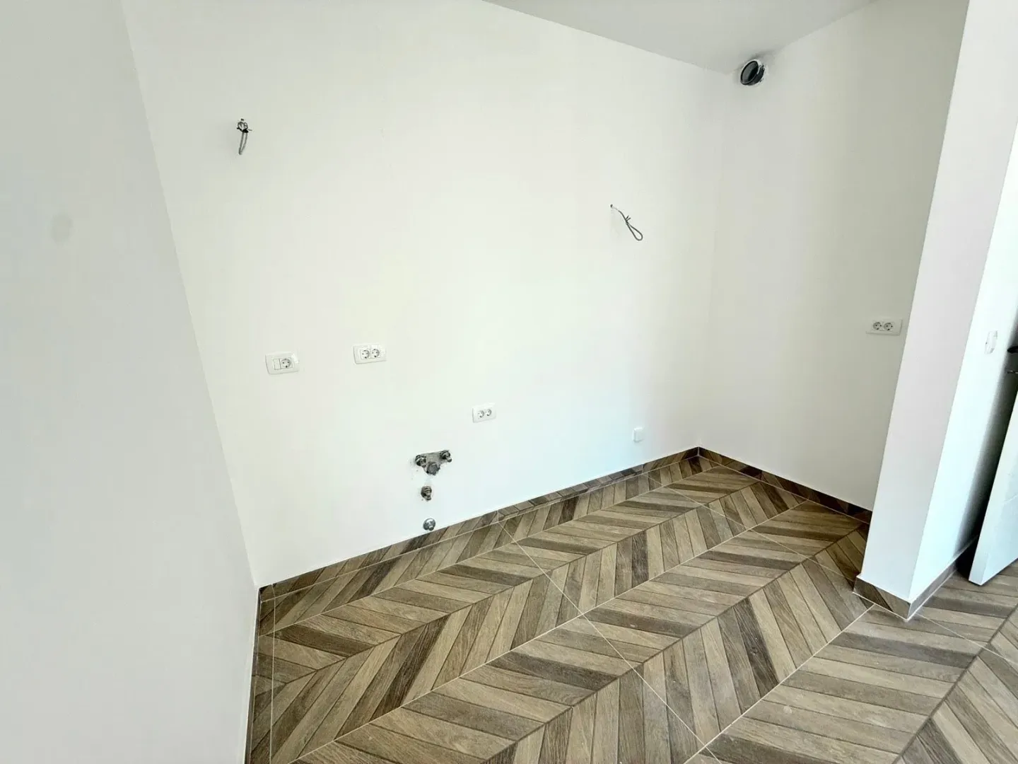 Empty space with ceramic floor tiles and kitchen connections.