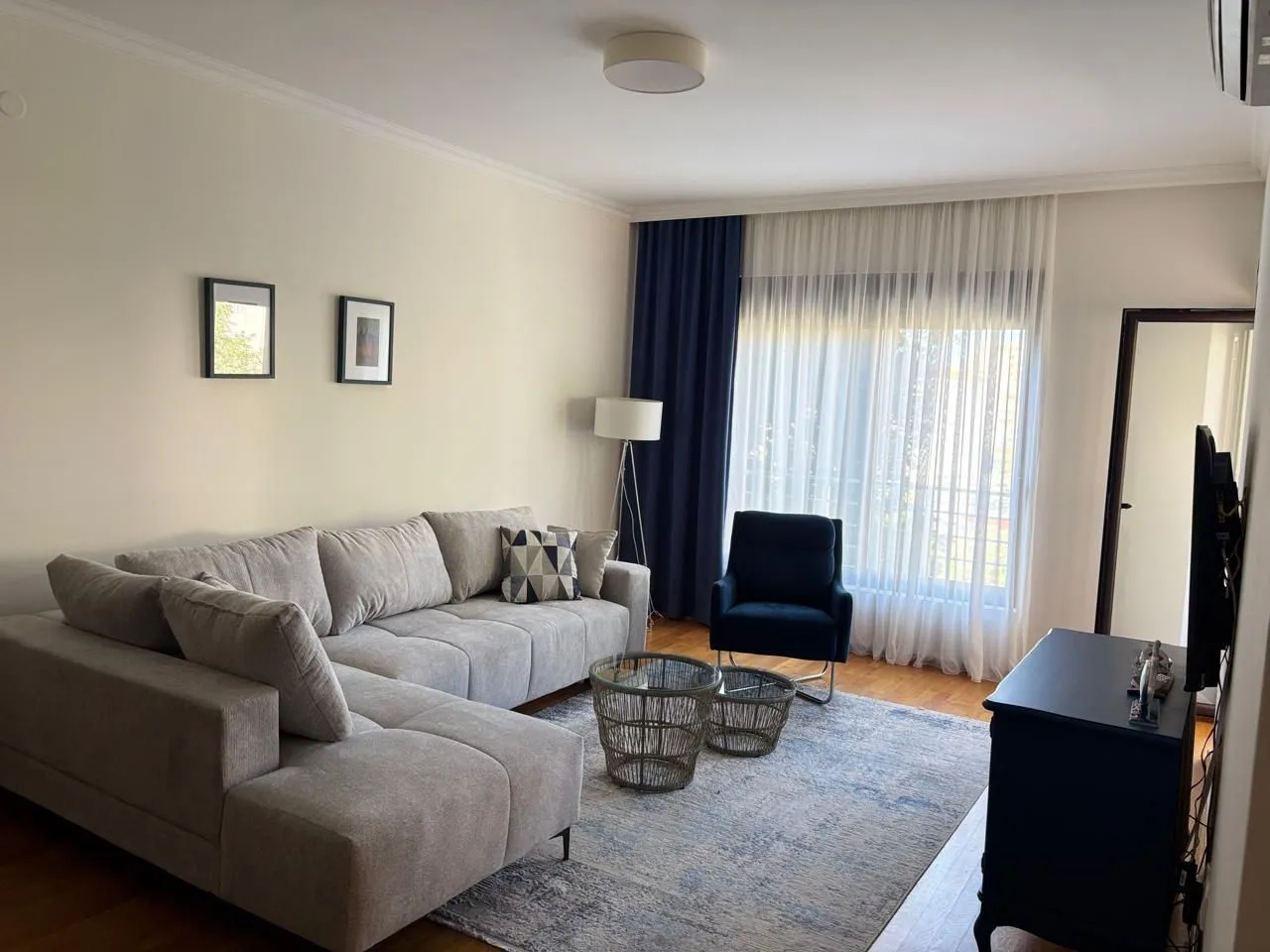 Living room with a sectional sofa, armchair, and a window with curtains.