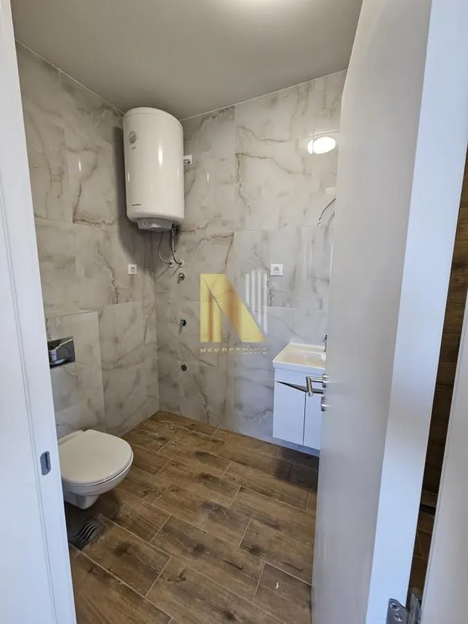 Manje kupatilo sa tuš kabinom, WC šoljom i bojlerom.
