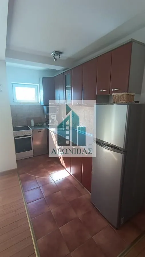 Kuhinja sa drvenim elementima, frižiderom i šporetom.