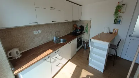 Manja kuhinja sa bijelim elementima, drvenom radnom pločom i šankom za ručavanje. - image 3