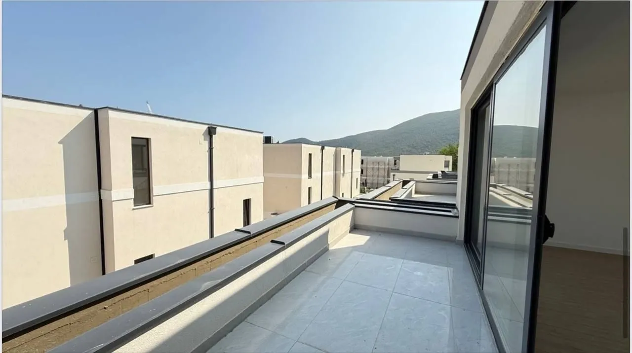 Spacious terrace with a view of surrounding buildings and hills.