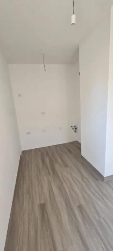 Prazna neuređena prostorija sa laminatom na podu i priključcima na zidu.