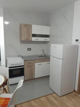 Small modern kitchen with white and wooden cabinets, a stove, and a refrigerator. - image 5