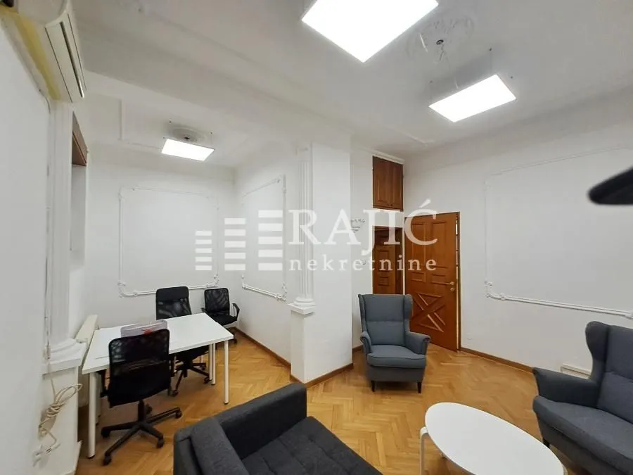 Spacious and bright room with seating furniture and an office desk.