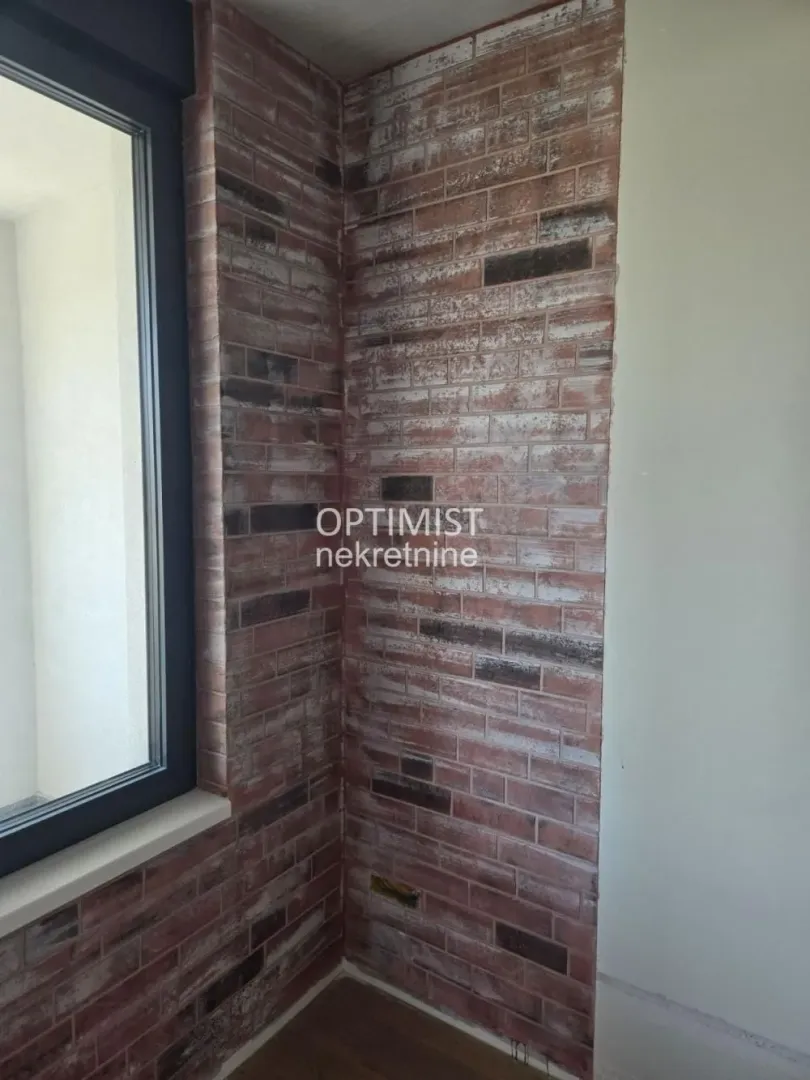 Detalj unutrašnjeg zida sa dekorativnom ciglom i prozorom.