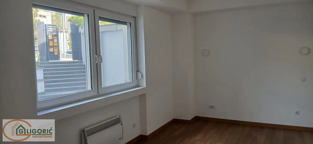 Prazna soba sa prozorom i belim zidovima.