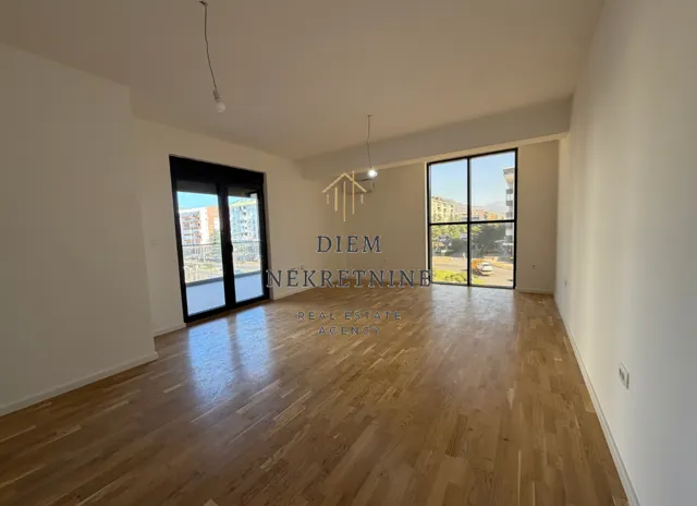 Empty living room with parquet flooring and large glass surfaces.