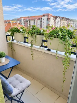 Namešten balkon sa stolom, stolicama i saksijama cveća sa pogledom na grad. - image 7