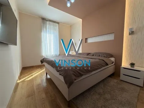 Nameštena spavaća soba sa bračnim krevetom, noćnim stočićem i TV-om na zidu. - image 6