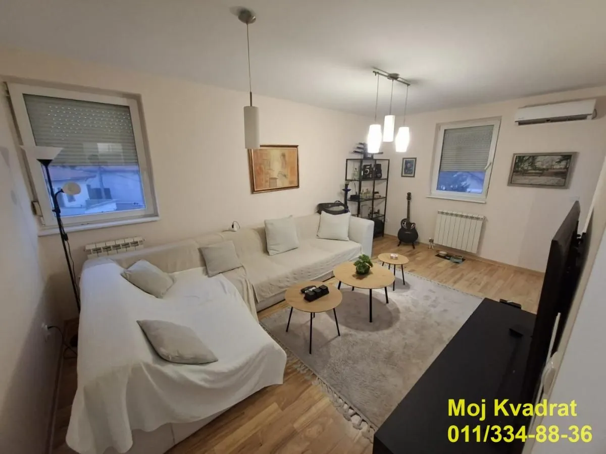 Dnevna soba sa garniturom, stočićima i televizorom.