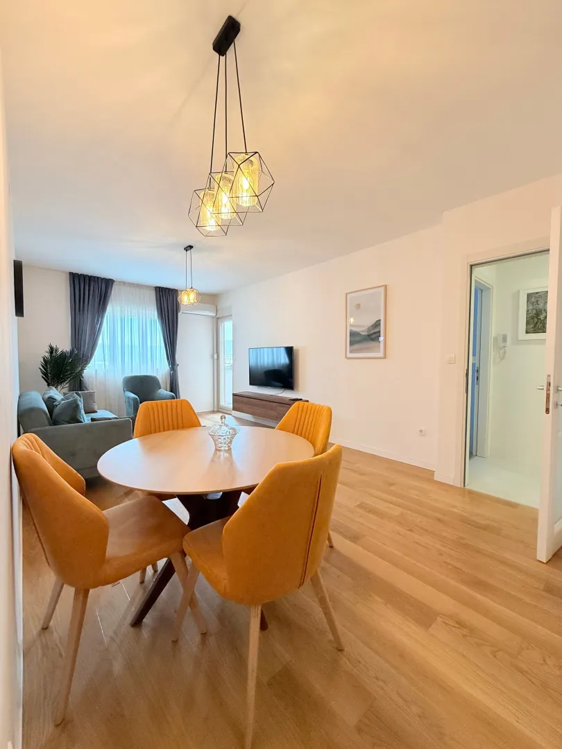 Dnevna soba sa trpezarijom, drvenim podom i modernim osvjetljenjem.