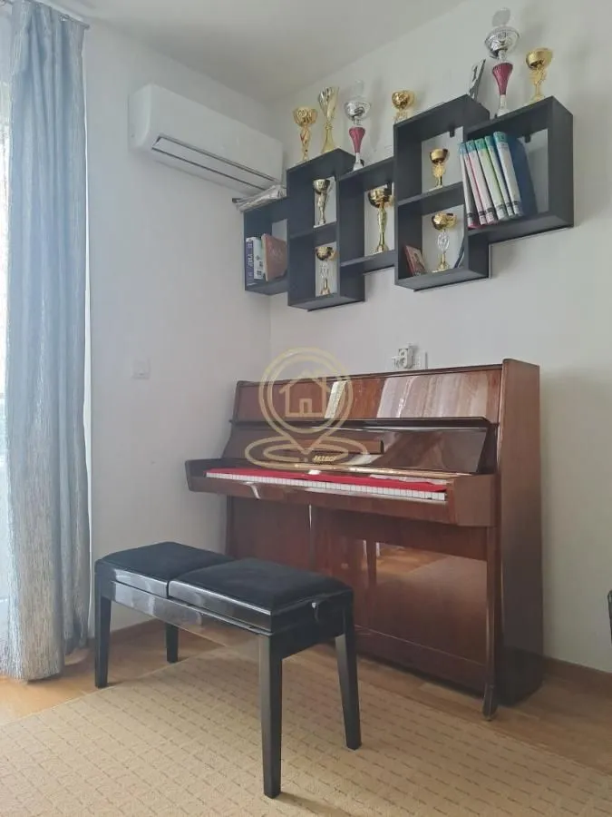 Living room with a piano and a wall shelf with trophies.