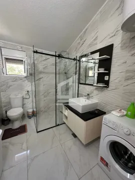 Bathroom with a walk-in shower, washbasin, toilet, and washing machine. - image 6