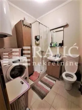 Smaller bathroom with a shower cabin, sink, toilet, and washing machine. - image 11