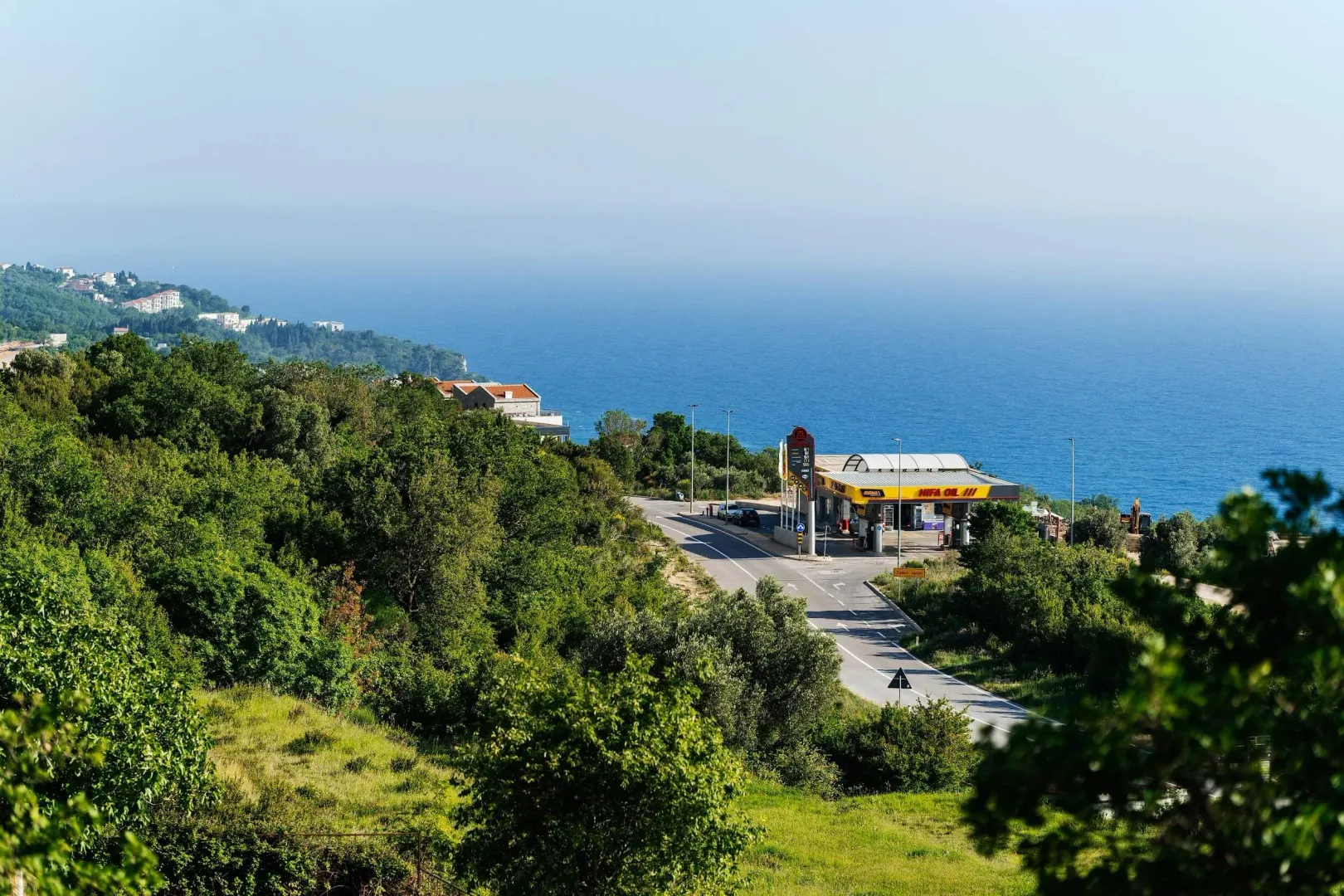View of the surrounding area, main road, and the sea with greenery.