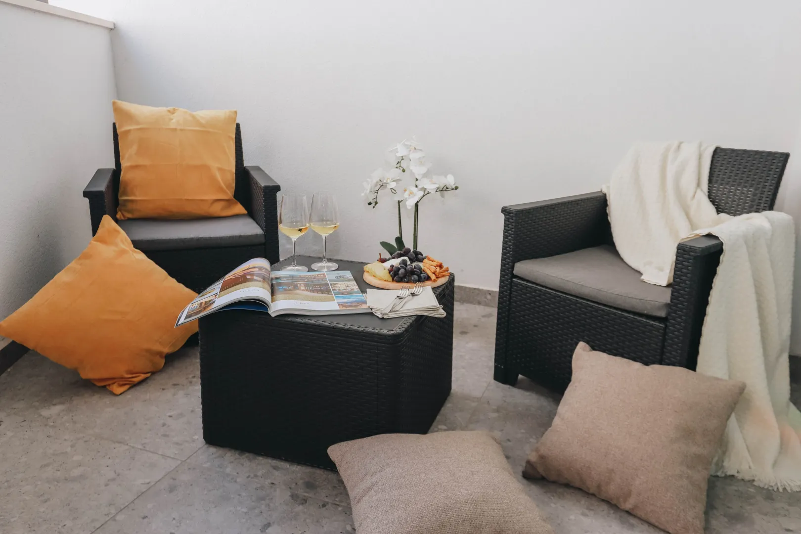 Furnished terrace with seating set, small table, decoration, and pillows.
