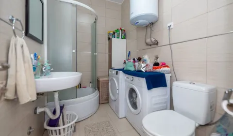 Bathroom with a shower cabin, washbasin, washing machine, and toilet. - image 10