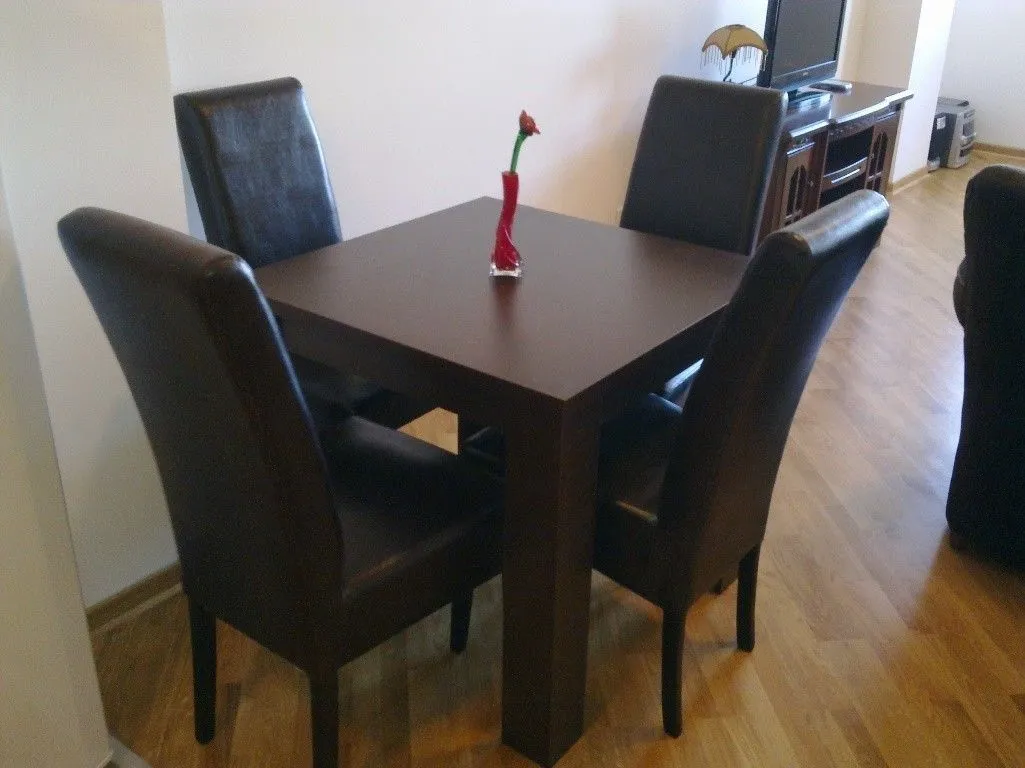 Dining table with four dark chairs in the living room area.