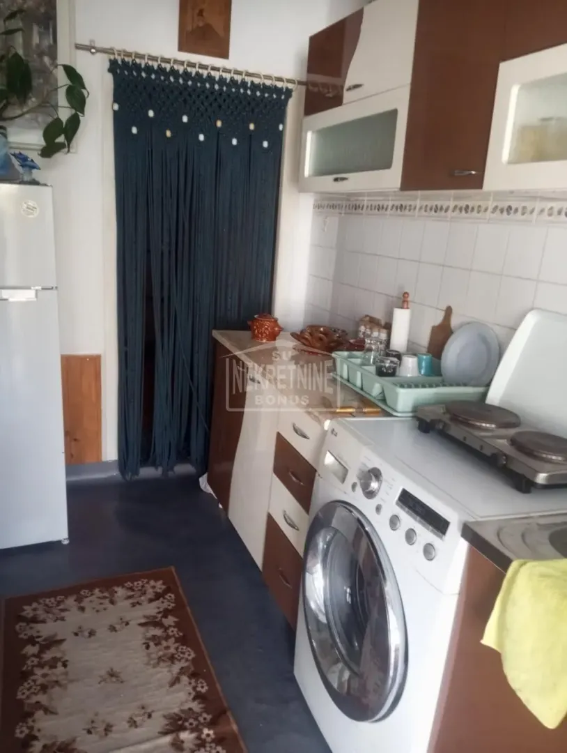 Manja kuhinja sa belim elementima, veš mašinom i frižiderom.