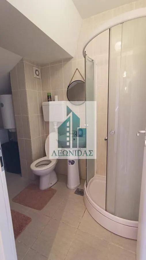 Bathroom equipped with a shower cabin, sink, and toilet.