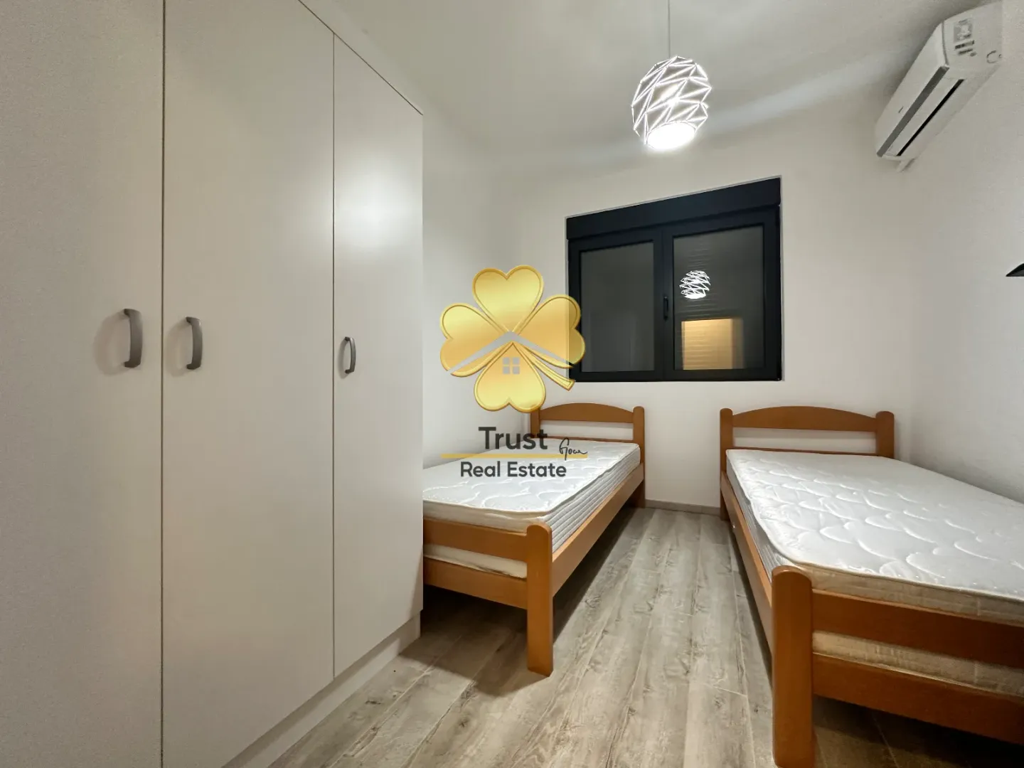 Bedroom with two wooden beds and a white wardrobe.