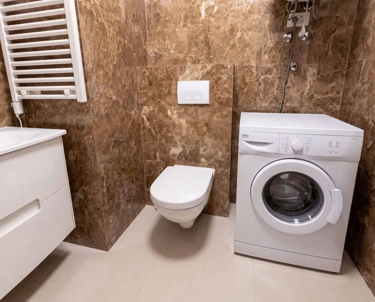 Modernly equipped bathroom with a washing machine and sanitary fixtures.