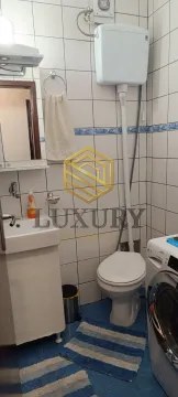 Manje kupatilo sa bijelim pločicama, umivaonikom, wc šoljom i veš mašinom. - image 6