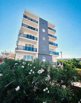 Pogled na spoljašnjost moderne stambene zgrade sa terasama i uređenim rastinjem u dvorištu. - image 6