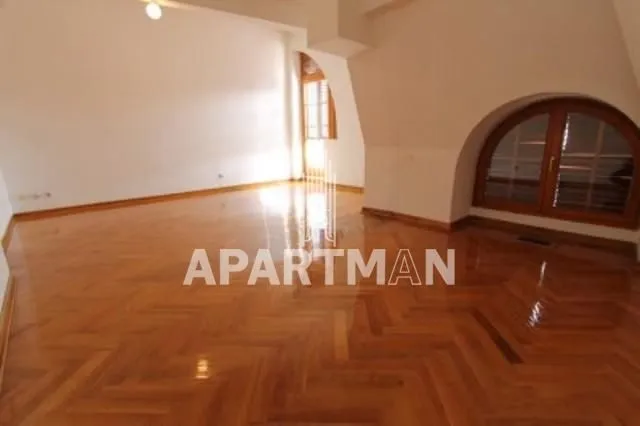 Empty living room with hardwood floors and an arched window.