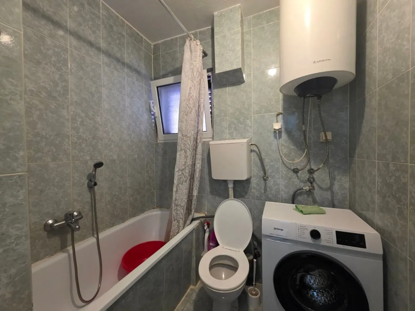 Bathroom with a bathtub, toilet, and washing machine.