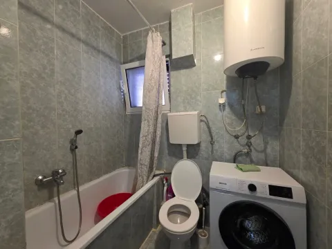 Bathroom with a bathtub, toilet, and washing machine. - image 15