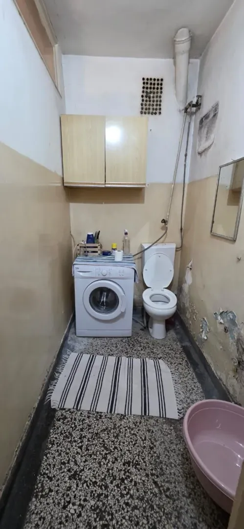 Manje kupatilo sa toaletom i veš mašinom.