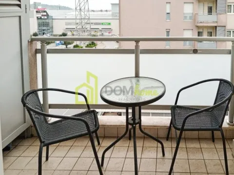 Namješten balkon sa stolom i dvije stolice i pogledom na grad. - image 3